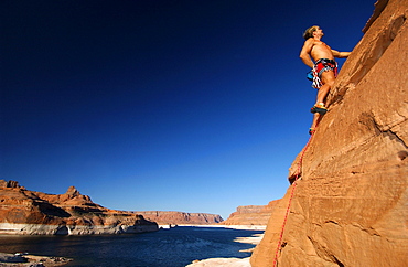 Man climbing up rock face, Lake Powell, Arizona, USA