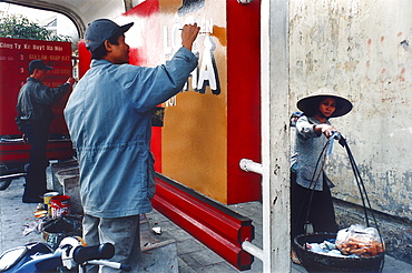 Man painting a poster, advertisement at the bus stop, Hanoi, Vietnam