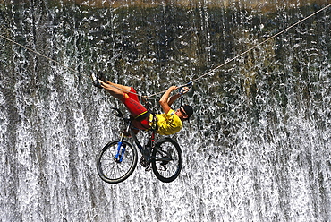 Mountain biker on a rope in front of waterfall