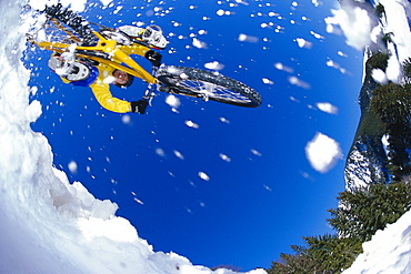 Mountainbiker jumping through snow, Alps, Austria