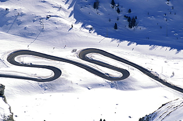 People skiing on a ski slope next to a serpentine, Passo Pordoi, South Tyrol, Italy