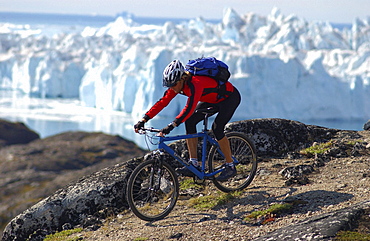 A man mountainbiking over rocks, Jakobshavn, Ilulissat, Greenland