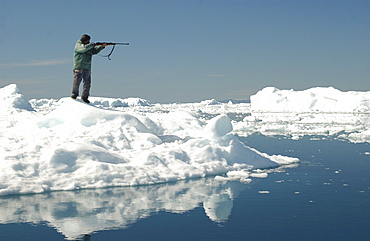 Hunter with rifle standing on the waterfront, Ilulissat, Greenland