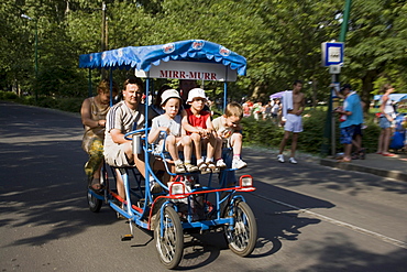 Family in a pedal car on Margaret Island, Family using a pedal car for driving over Margaret Island, Budapest, Hungary