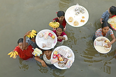 Women vendors standing waist-high in river, carrying fruit, Myanmar