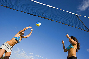 Two young woman playing beach volleyball, Apulia, Italy