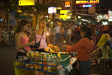 People standing around a food stand at Th Khao San Road in the evening, Banglamphu, Bangkok, Thailand