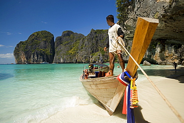 Boatman standing on a long tail boat and holding a rope, Maya Bay, a beautiful scenic lagoon, famous for the Hollywood film "The Beach", Ko Phi-Phi Leh, Ko Phi-Phi Islands, Krabi, Thailand, after the tsunami