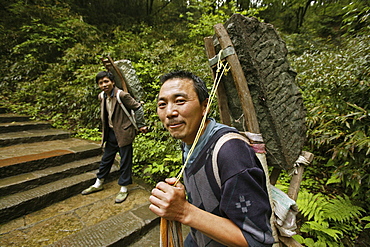 Two porters carrying heavy load on the pilgrimage route, Emei Shan, Sichuan province, China, Asia