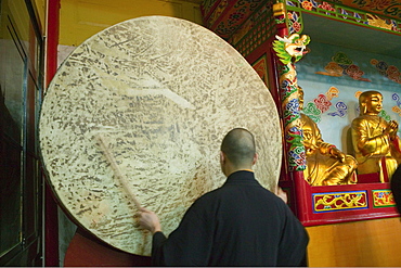 Monk standing in front of a gong, Wannian monastery, Emei Shan, Sichuan province, China, Asia