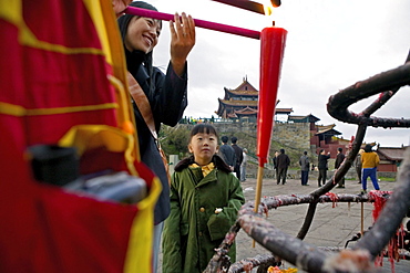 Woman and child lighting a candle in the morning, Emei Shan mountains, Sichuan province, China, Asia