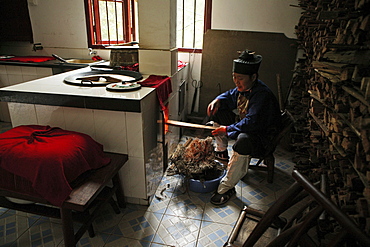 A nun heating up the stove in the kitchen of Nunnery Huanting, Heng Shan South, Hunan province, China, Asia