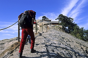 Fish Back Ridge, pilgrim path along stone steps with worn down chain handrail to South Peak Monastery, western tourist with backpack, Hua Shan, Shaanxi province, Taoist mountain, China, Asia