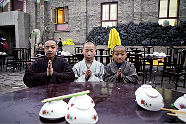 Young monks eating lunch, coal used cooking in the background, during birthday celebrations for Wenshu, Mount Wutai, Wutai Shan, Five Terrace Mountain, Buddhist Centre, town of Taihuai, Shanxi province, China