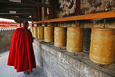 Lama monk turns the prayer wheels at the base of the Great White Pagoda, during the birthday celebrations for Wenshu, Tayuan Monastery, Wutai Shan, Five Terrace Mountain, Buddhist Centre, town of Taihuai, Shanxi province, China