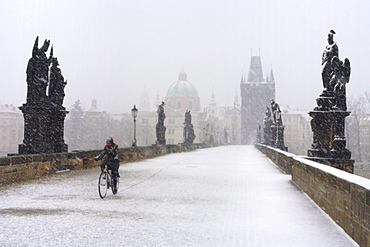 Man on a bicycle riding over Charles Bridge, Prague, Czech Republic