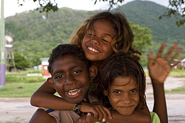 Portrait of three smiling Aborigine children at dusk, Palm Island, Queensland, Australia