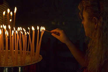 Person lighting candles in a cave of the monastery of the Apocalypse, Patmos, Dodecanese Islands, Greece