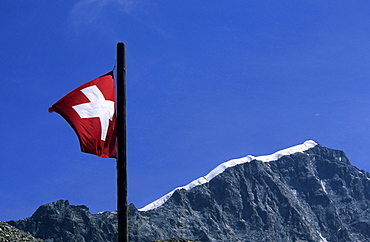 swiss flag with ridge Biancograt, hut Tschiervahuette, Bernina range, Oberengadin, Grisons, Switzerland