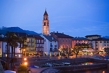 Harbour and harbour promenade with spire of church Santi Pietro Paolo in background in the evening, Ascona, Lake Maggiore, Ticino, Switzerland