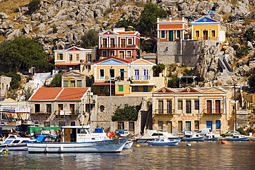 Fishing boats and rowboats anchoring in harbour Gialos, picturesque houses in background, Simi, Symi Island, Greece