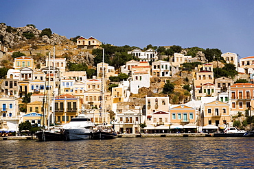 Yacht and sailing boats anchoring at quay of harbor Gialos, Simi, Symi Island, Greece