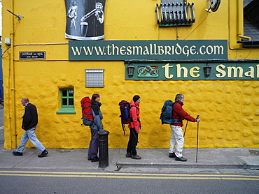 Hikers walking the Dingle Way outside a colorful pub, Dingle, Dingle Peninsula, County Kerry, Ireland