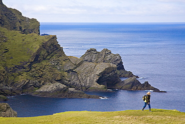 A woman walking along the coast of the Nature Protection Area, Hermaness, Island of Unst, Shetland islands, Scotland, Great Britain