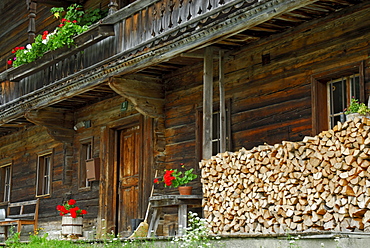 traditional farmers house with flower decoration and pile of fire wood in front, Ellmau, Kaiser range, Tyrol, Austria