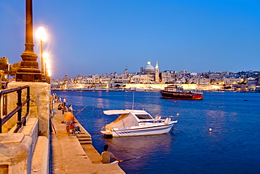 Anglers sitting on the promenade in the evening, view at the town of Valletta, Sliema, Malta, Europe