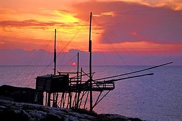 Silouette of a fishing net frame at sunrise, Trabucco, Punta Lunga near Vieste, Gargano, Apulia, Italy