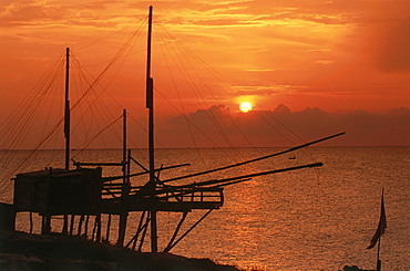 Silouette of a fishing net frame at sunrise, Trabucco, Punta Lunga near Vieste, Gargano, Apulia, Italy