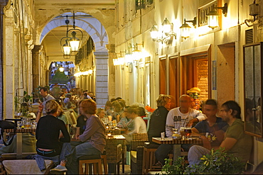 People sitting in cafes under the arcades of Liston, Corfu, Ionian Islands, Greece