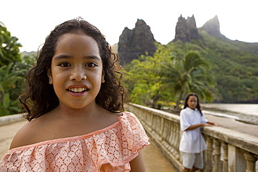 Two girls in front of peaks at Hatiheu, Nuku Hiva, Marquesas, Polynesia, Oceania