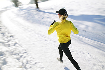 Woman jogging on snowy road, Styria, Austria