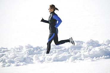 Woman jogging on snowy road, Styria, Austria