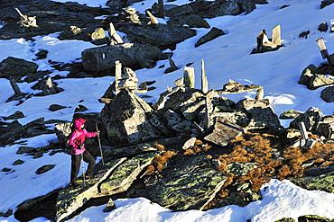 Woman walking through snow covered rocks and cairns, Peterskoepfl, Zillertal range, Zillertal, Tyrol, Austria