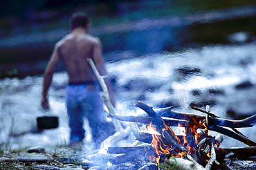 Campfire, topless man in background, riverside of Isar, Upper Bavaria, Germany