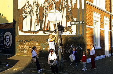 Children playing in front of a painted wall of a house, Falls Road, Belfast, County Antrim, Ireland, Europe