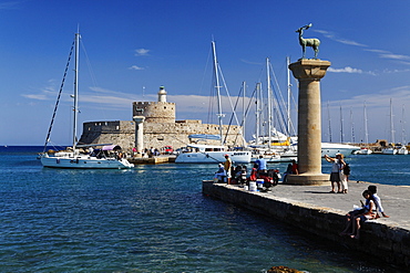 Columns at the entrance of Mandraki harbour and the Agios Nikolaos Fortress in the sunlight, Rhodes town, Rhodes, Dodecanese Islands, Greece, Europe