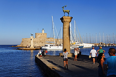 Columns at the entrance of Mandraki harbour and the Agios Nikolaos Fortress in the sunlight, Rhodes town, Rhodes, Dodecanese Islands, Greece, Europe