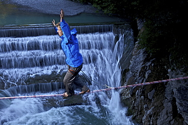 Young man balancing on a highline over a stream, Fuessen, Bayern, Deutschland, Europe