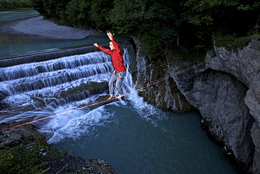 Young man balancing on a highline over a stream, Fuessen, Bavaria, Germany, Europe