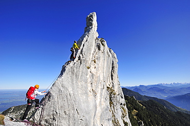 Young woman belaying climber at pinnacle, Kampenwand, Chiemgau Alps, Chiemgau, Upper Bavaria, Bavaria, Germany