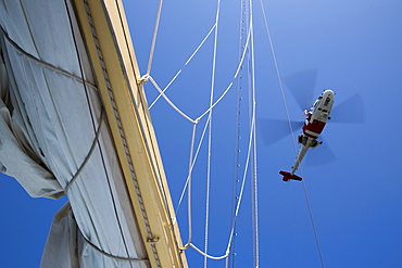 Man lowers himself from Swedish Sjoefartsverket rescue helicopter during rescue exercise on sailing cruise ship Star Flyer (Star Clippers Cruises), near Visby, Gotland, Sweden