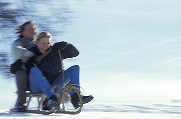 Couple sledding downhill