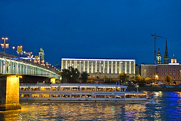 An excursion boat driving on the Danube at night, University of Art in the background, Linz, Upper Austria, Austria