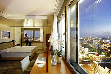 Man looking out of a hotel window at Alexanderplatz, Berlin, Germany