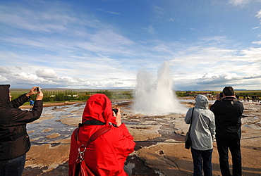 Tourists taking photos of the Strokkur geyser in the valley of Haukadalur at the golden circle, Iceland, Europe