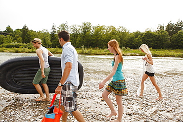 Young people with a rubber dinghy on the Isar riverbank, Munich, Bavaria, Germany